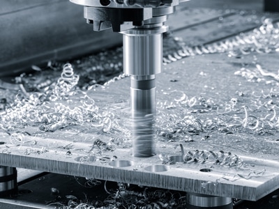 A CNC milling machine cuts metal on a worktable, showcasing precision in CNC machining processes.