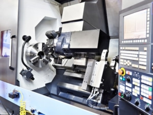 Close-up view of a CNC lathe machine with a control panel and metal components, highlighting its role in subcontract engineering within a modern industrial setting.