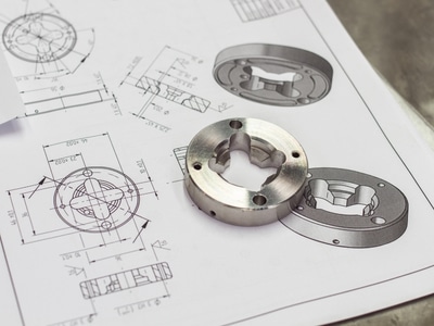 Close-up of a metal component on an engineering blueprint for CNC component manufacturing.